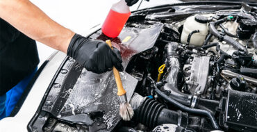 Person using a brush and soap to clean a car's engine
